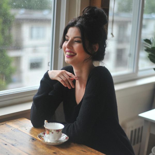Person sitting peacefully with a cup of tea by a window.